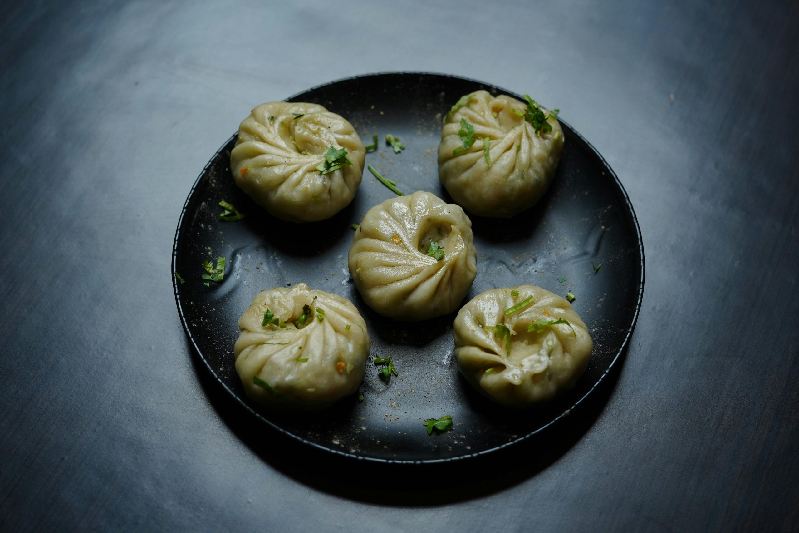 Plate of Tibetan dumplings (momos) garnished with herbs, perfect for food photography.